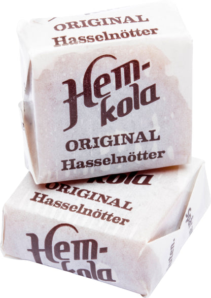 Swedish Candy Club's Hem-kola original hasselnötter individually wrapped candies. Two stacked, showing white paper wrappers with brown text.